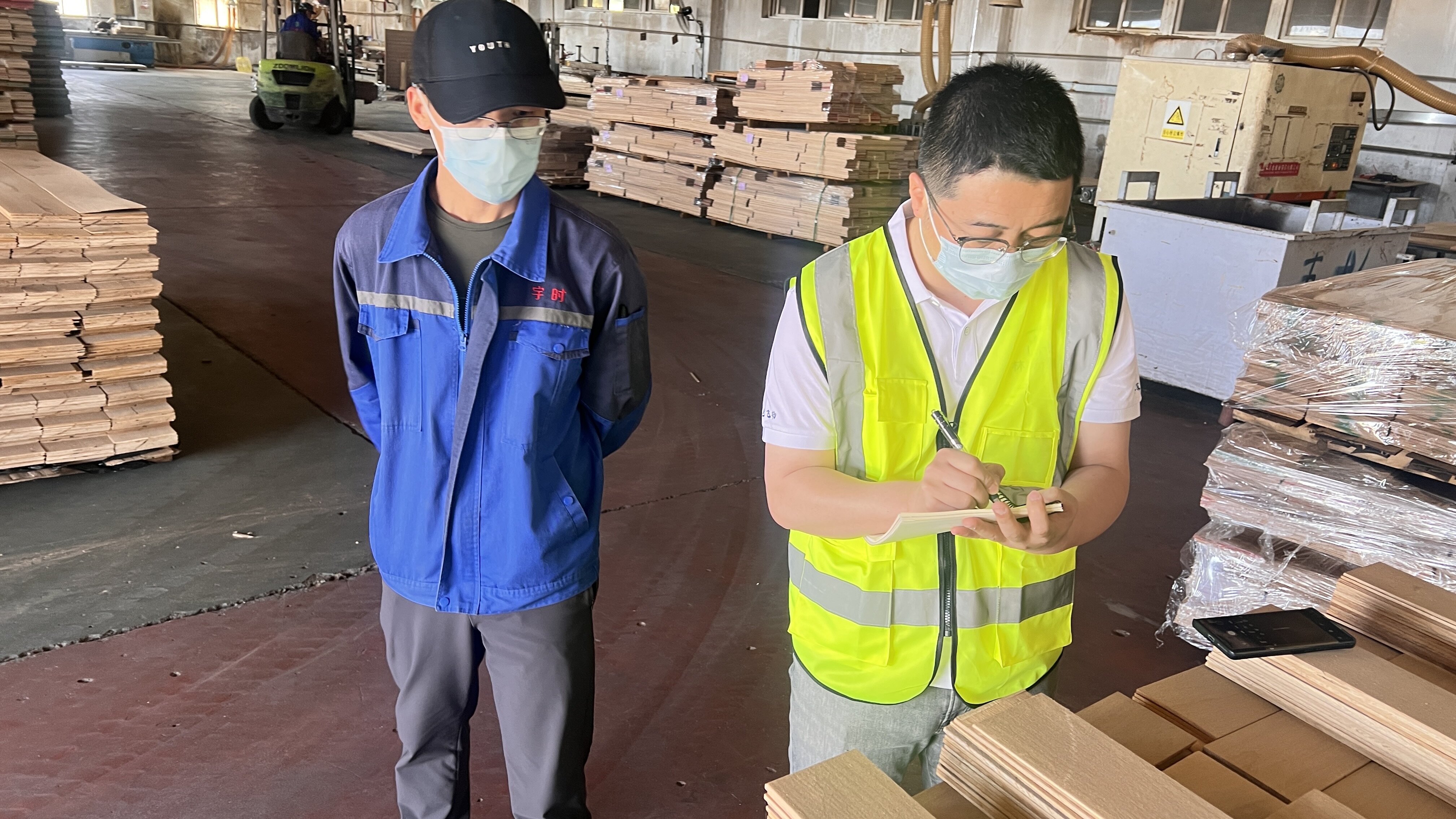 Auditor verifies ledger at a wood factory