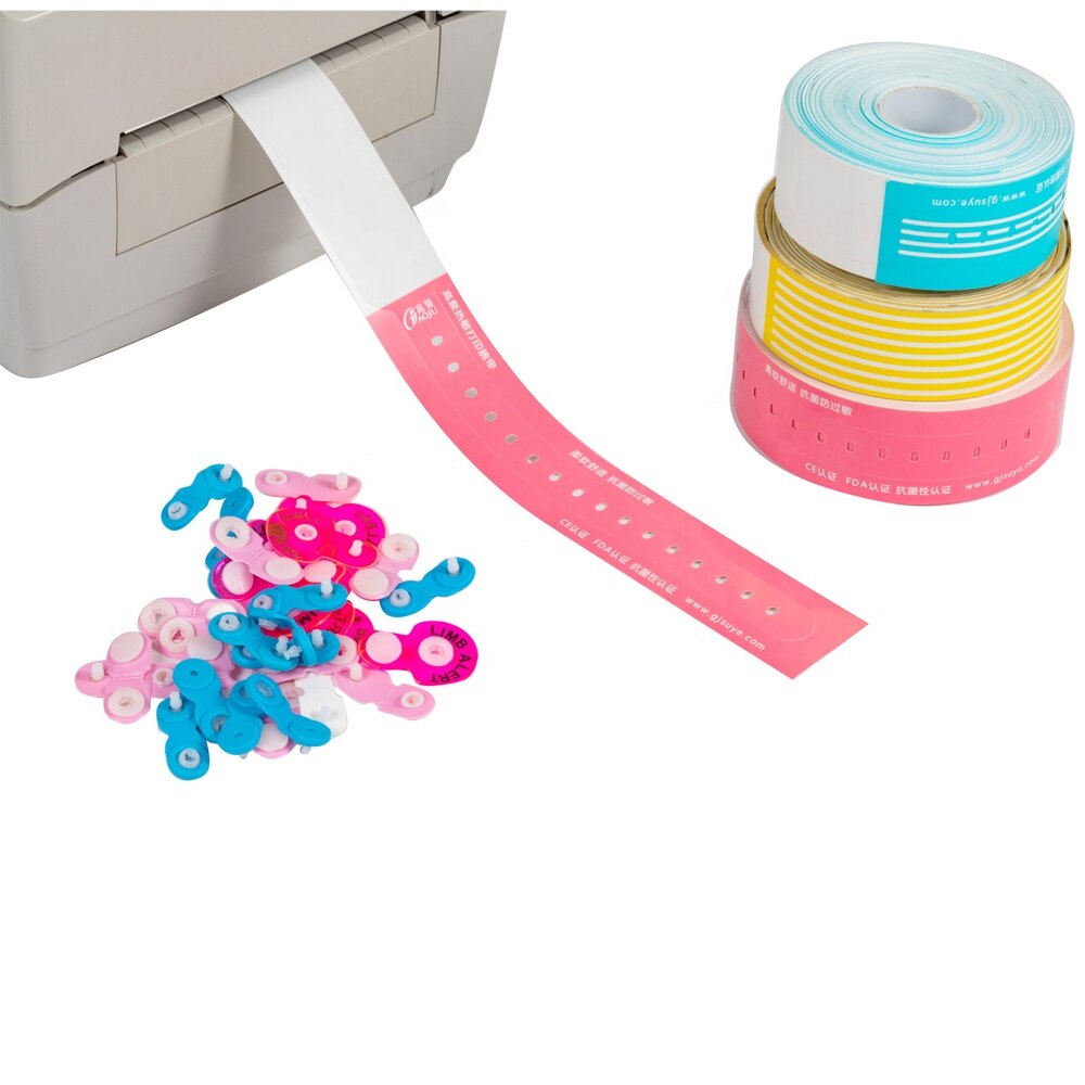 Thermal printer feeding a pink wristband band beside stacked rolls and plastic clip fasteners