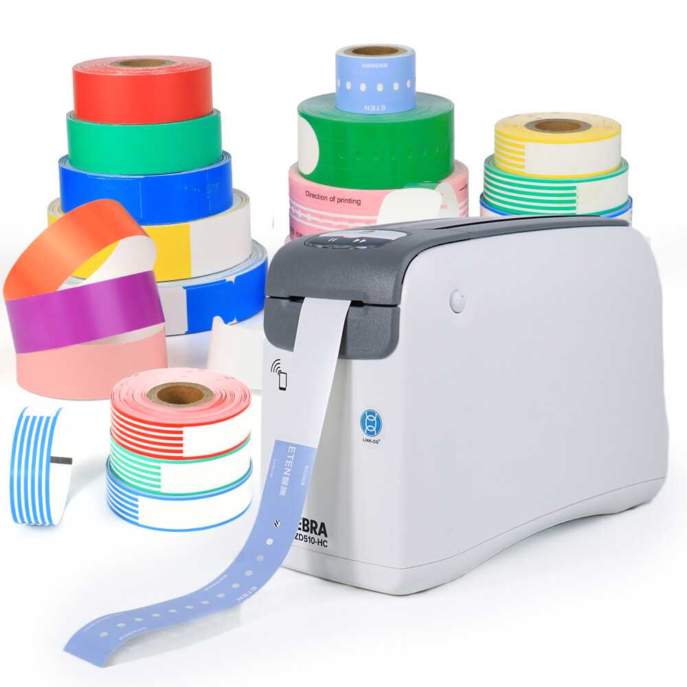 Stacks of colored direct thermal wristband rolls beside a desktop thermal wristband printer