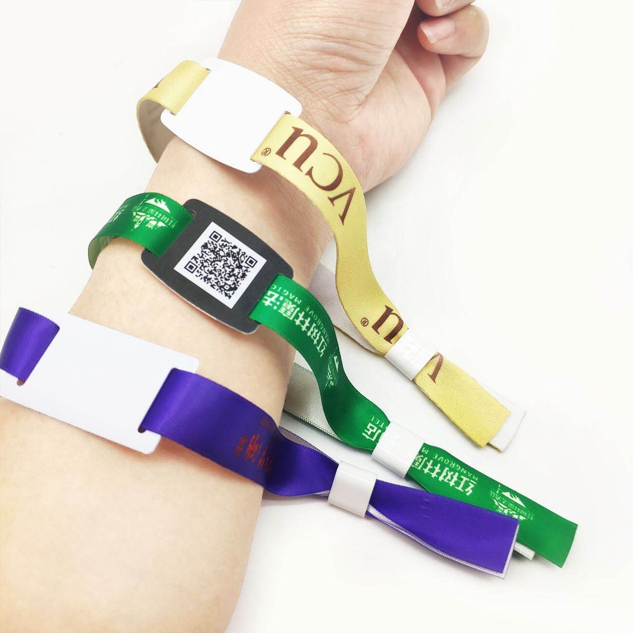 Multiple fabric wristbands with QR codes and custom logos in green purple and yellow colors