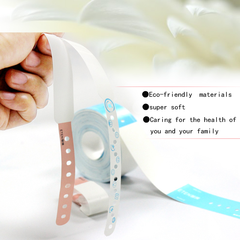 Hand holding ultra-soft eco-friendly patient wristband strips in white and pink beside a wristband roll