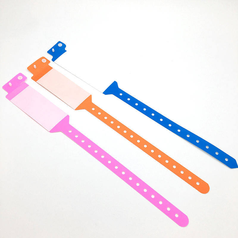 Pink, orange and blue disposable patient wristbands laid flat with writable panels