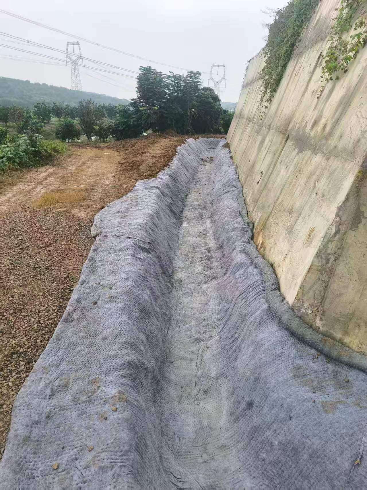 湖北玖坤国标水泥毯宜昌挡土墙侧边排水沟防渗铺装实拍,阻断雨水渗入墙体防滑移。
