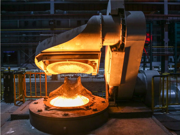 Molten steel being poured in a dark casting foundry producing shredder wear parts