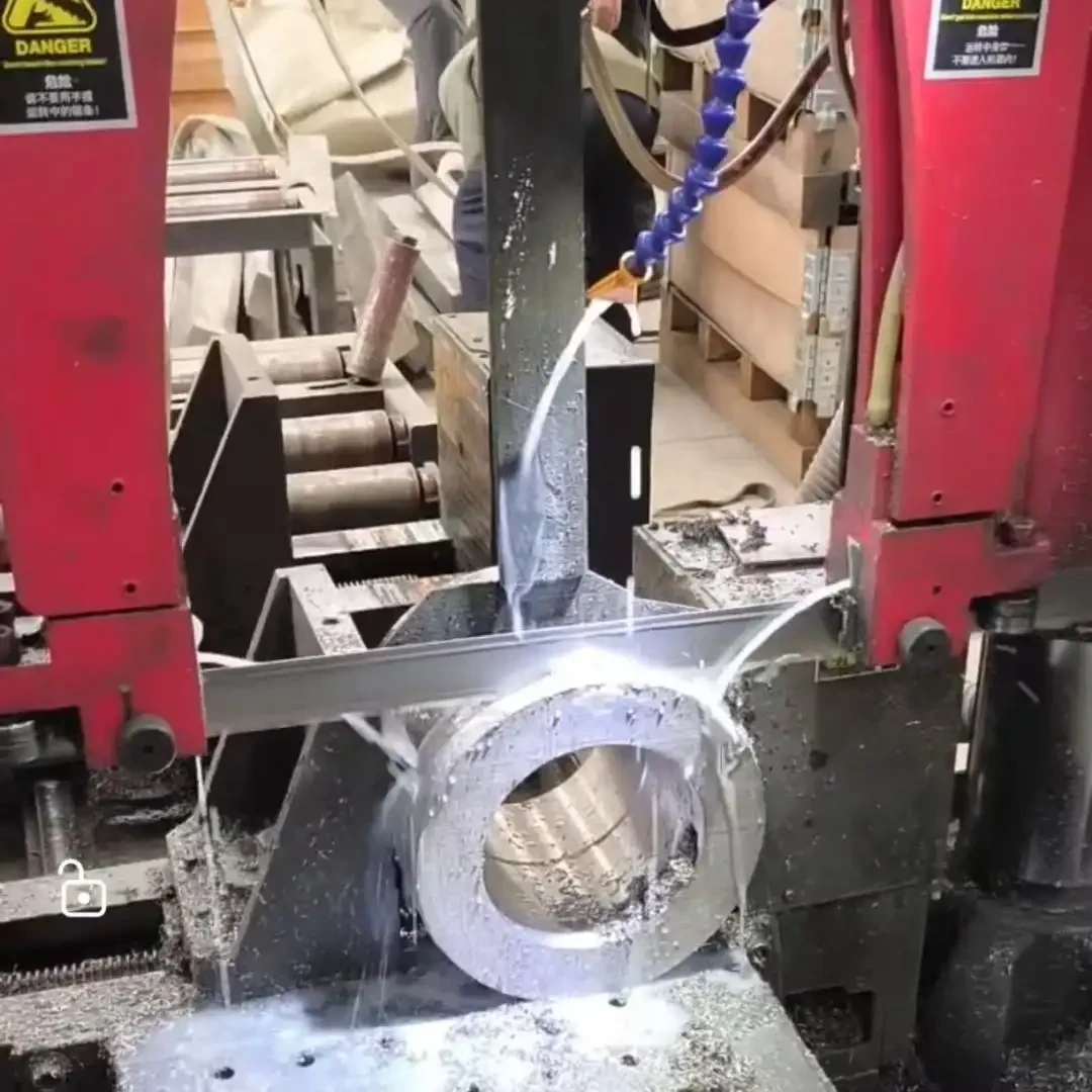 Bandsaw blade cutting a thick-walled steel ring with flood coolant