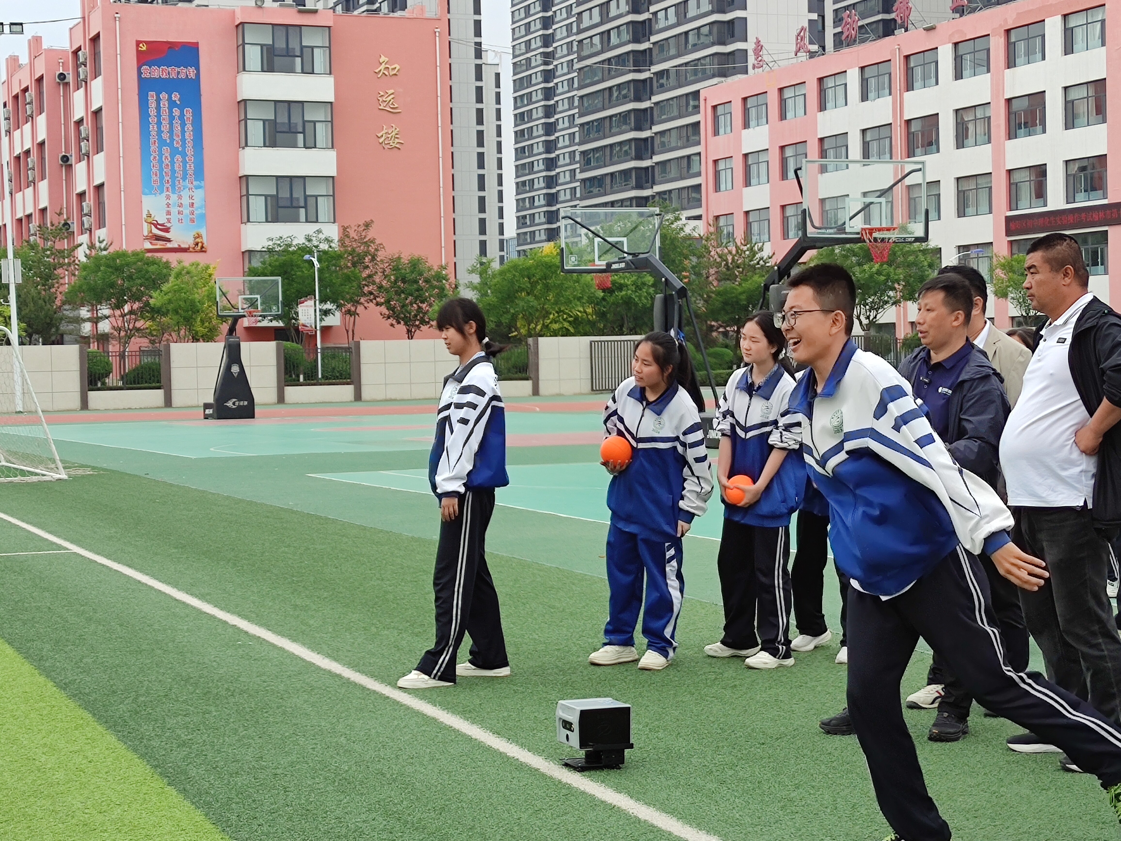 学生在绿色人造草坪上进行实心球投掷测试，体测仪放置在地面监测
