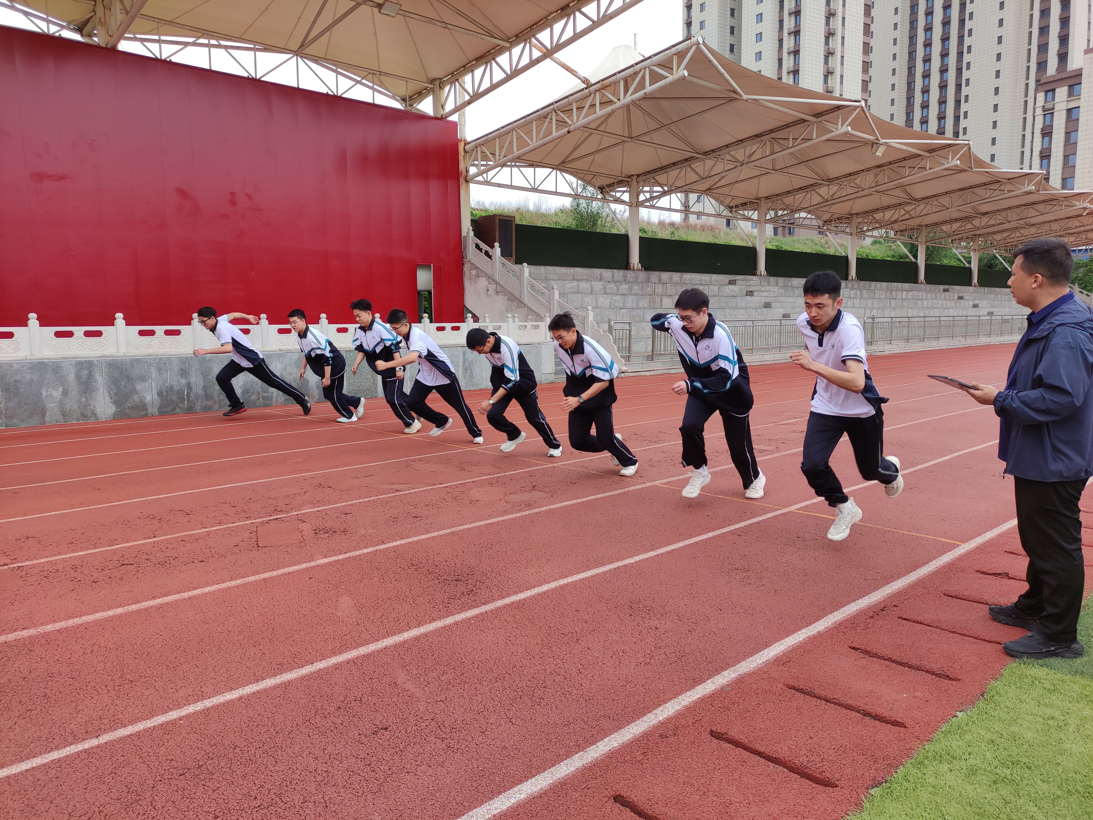 学生在红色塑胶跑道上进行50米起跑测试，体测仪在跑道旁实时监测