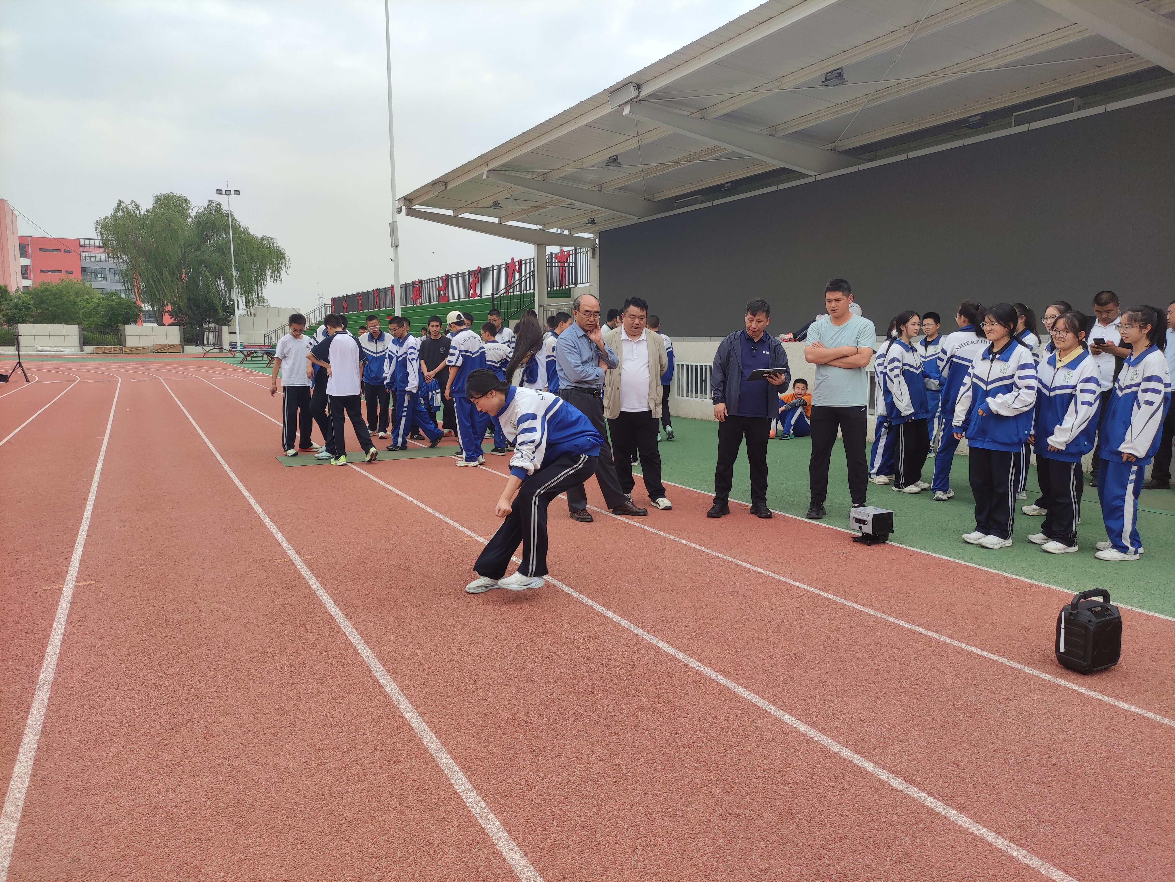 学生在跑道上进行立定跳远测试，体测仪放置在起跳线旁监测